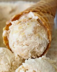 Close up of an apple ice cream cone resting in a tub of apple ice cream.