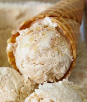 Close up of an apple ice cream cone resting in a tub of apple ice cream.