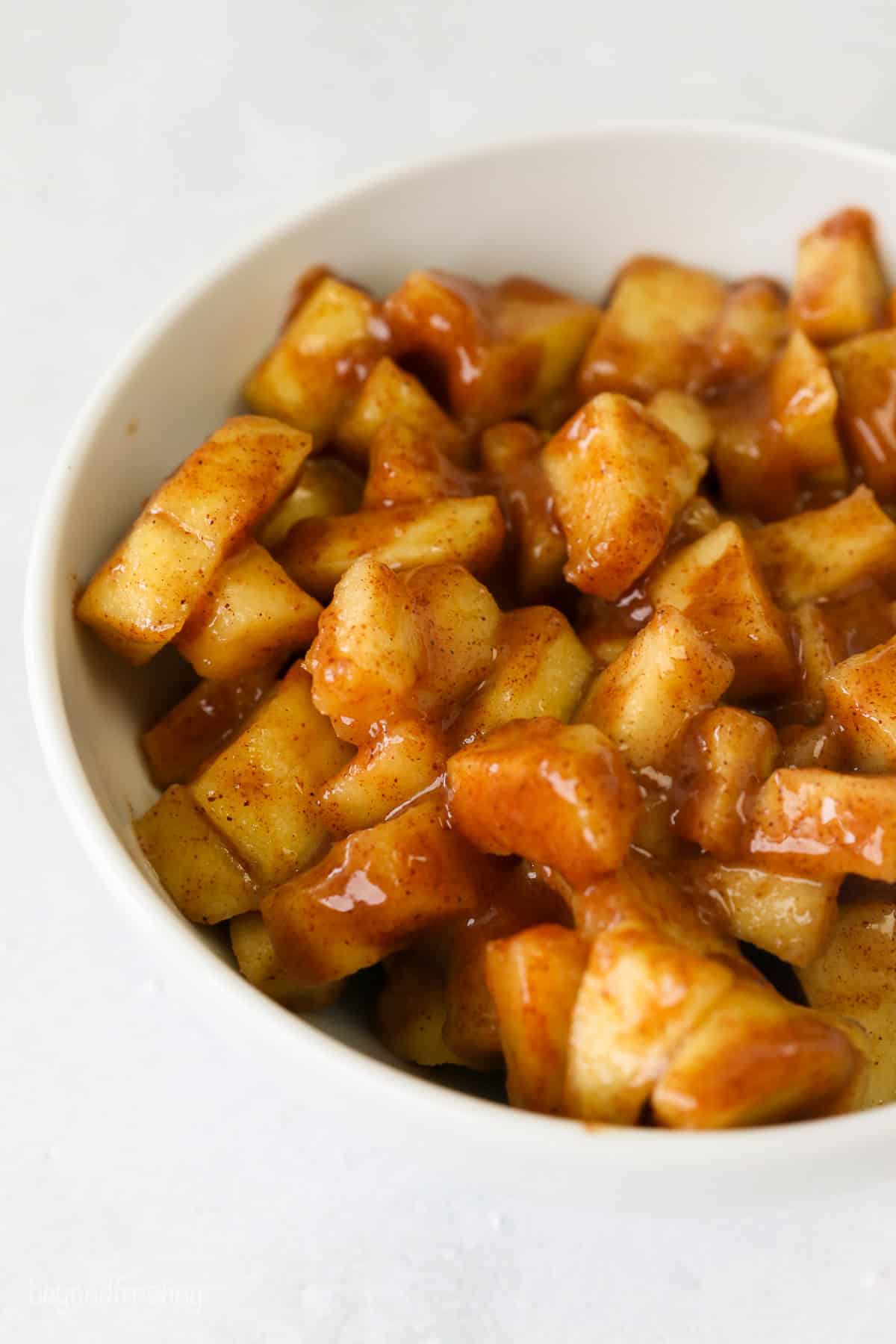 Close up of apple pie filling in a white bowl.