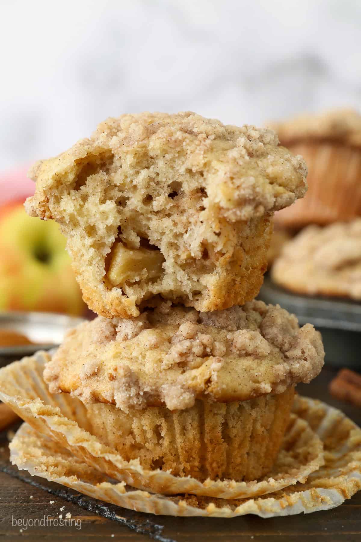 Two apple muffins stacked on top of one another, with a bite missing from the top muffin.