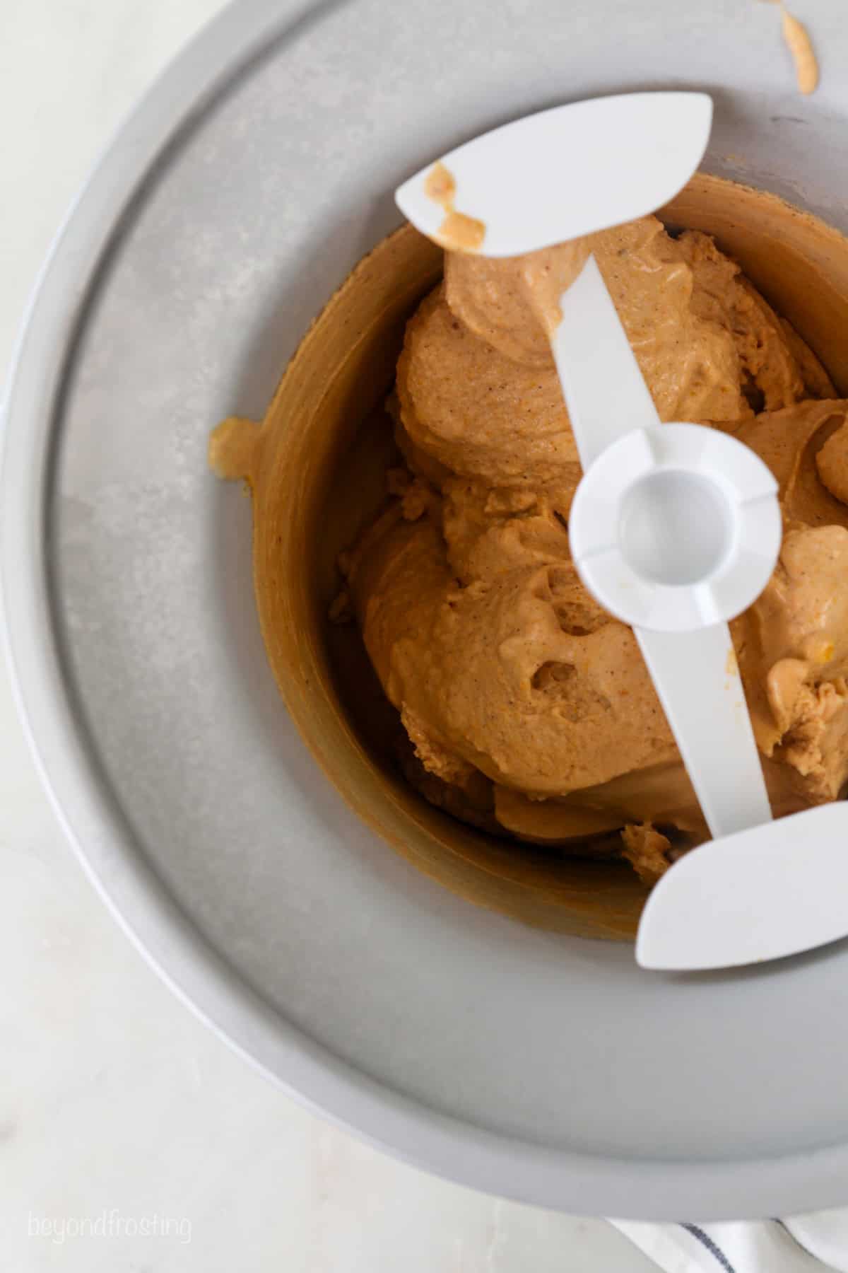 Overhead view of sweet potato ice cream churning inside the ice cream maker.