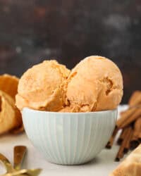 Two scoops of sweet potato ice cream in a light teal striped bowl