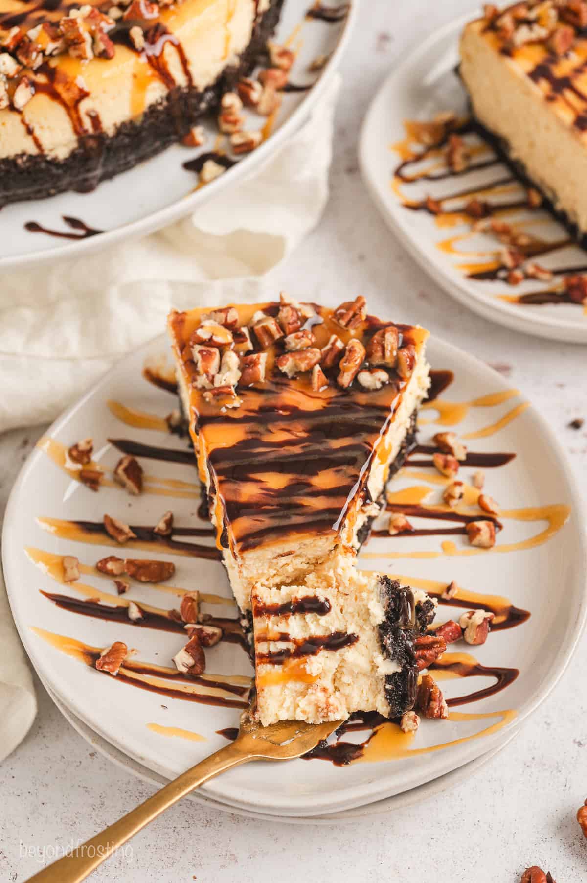 Overhead view of a slice of Turtle cheesecake on a plate with a forkful resting at the end.