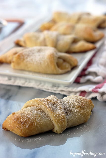 Close-up of an Apple cheesecake croissant in front of a platter of croissants