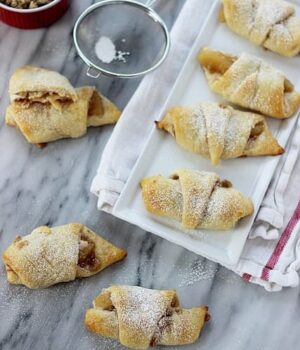 A few Apple cheesecake croissant pastries stuffed with apple pie filling and topped with powdered sugar