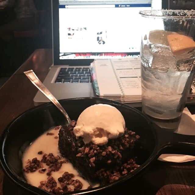 A slice of chocolate cake with ice cream in front of a laptop