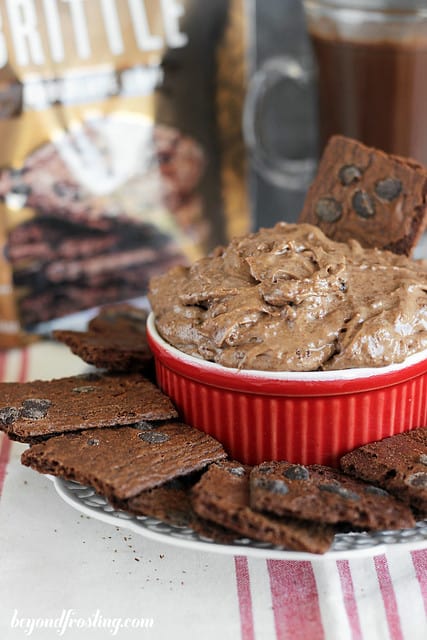 A bowl of Brownie Batter Hot chocolate dip surrounded by pieces of Brownie Brittle on a plate