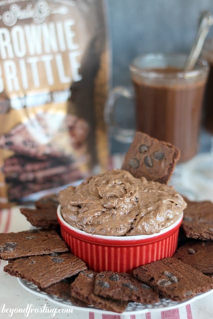 Brownie Brittle Hot Chocolate Dip in a red ramekin surrounded by Brownie Brittle pieces