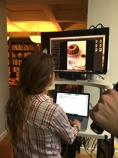 A woman editing a picture of a bundt cake on a computer screen