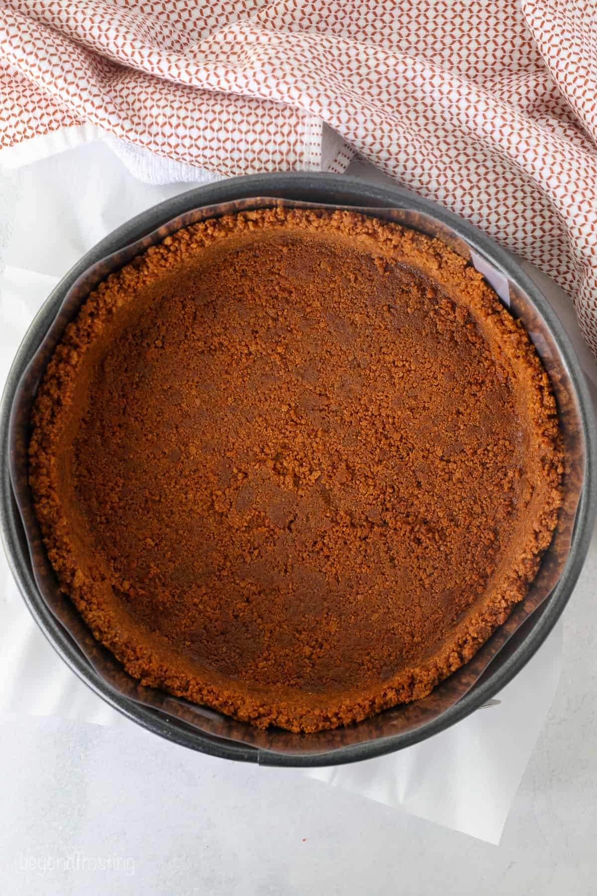 Overhead view of a Biscoff cookie crust pressed into a springform pan.