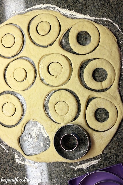 Overhead view of donuts being cut out of a big piece of dough