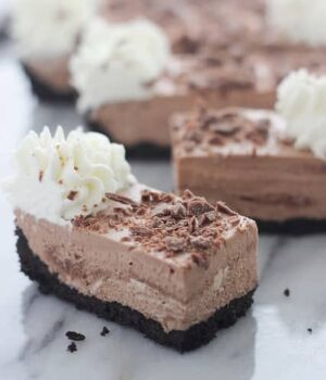 A piece of chocolate mousse tart with whipped cream and chocolate shavings on top plus more pieces in the background