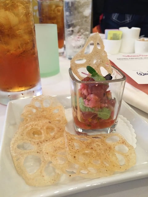 A glass of spicy tuna tartar with lotus root crisps