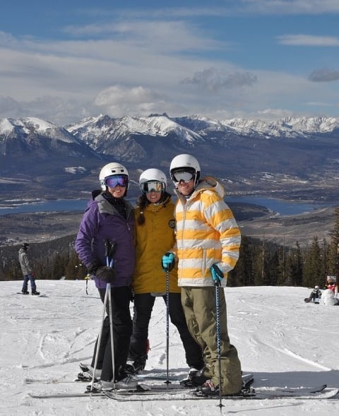 Three friends posing at the top of a ski slope