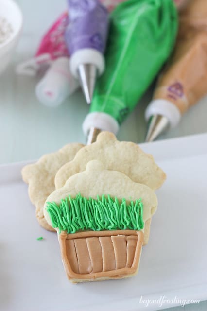 Overhead view of partially decorated flower pot cookies with piping bags of frosting