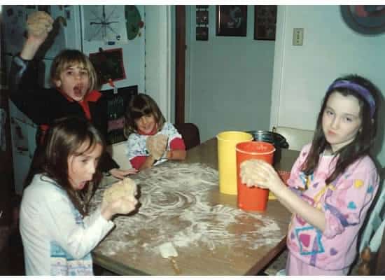 Four girls playing with dough at a kitchen table