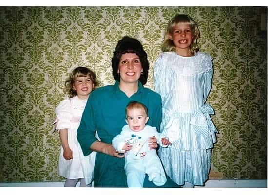 A mom posing with 3 children in the 1980's