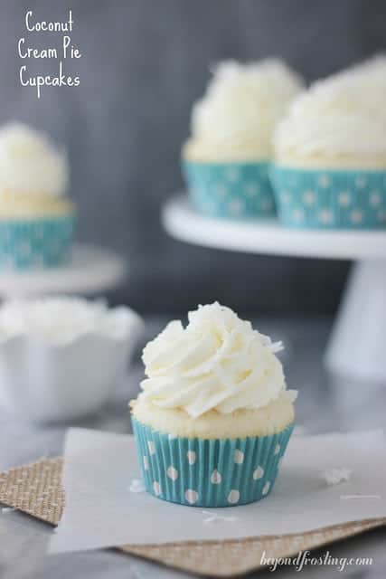 Coconut Cream Pie Cupcake on a napkin in front of cupcakes on a cake stand