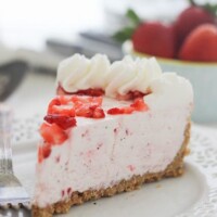 A slice of Strawberry Marshmallow Pie with a graham cracker crust on a white plate.