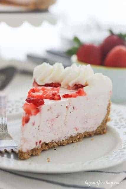 A slice of Strawberry Marshmallow Pie with a graham cracker crust on a white plate.