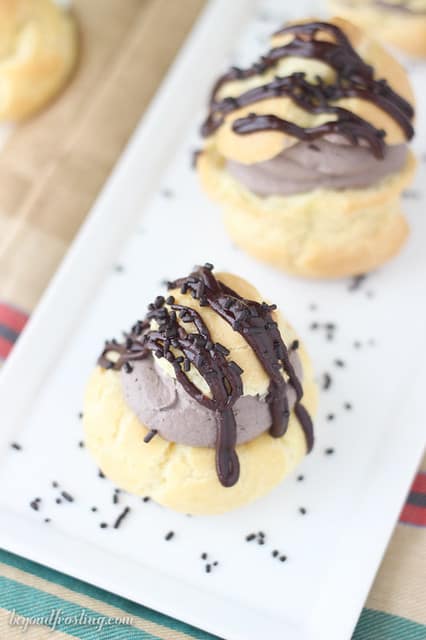 Overhead view of two chocolate cream puffs on a platter