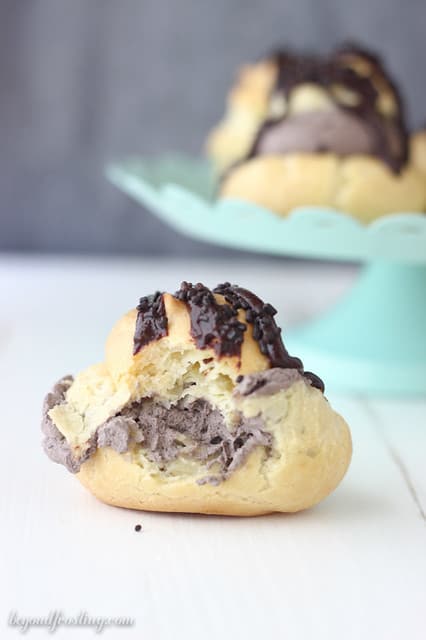 Side view of a chocolate cream puff with a bite removed
