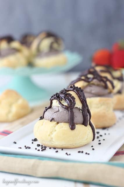 Close-up of a few chocolate cream puffs lined up on a platter