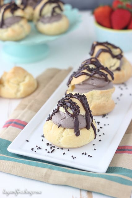 Three chocolate cream puffs lined up on a platter