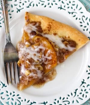 Overhead view of a slice of peach pizza on a plate next to a fork.