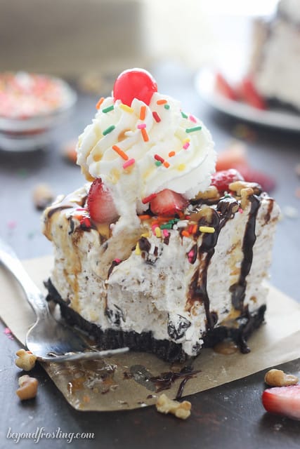 Close-up view of a serving of Banana Split S'mores Ice Cream Cake on a piece of parchment paper with a bite removed