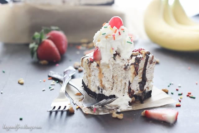 A serving of Banana Split S'mores ice cream cake on a piece of parchment paper with a bite removed