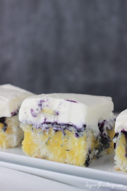 Pieces of Blueberry Cheesecake Poke Cake on a white platter