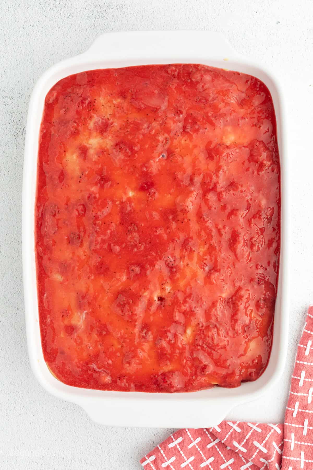 Overhead view of a vanilla cake topped with sweetened condensed milk and strawberry sauce.
