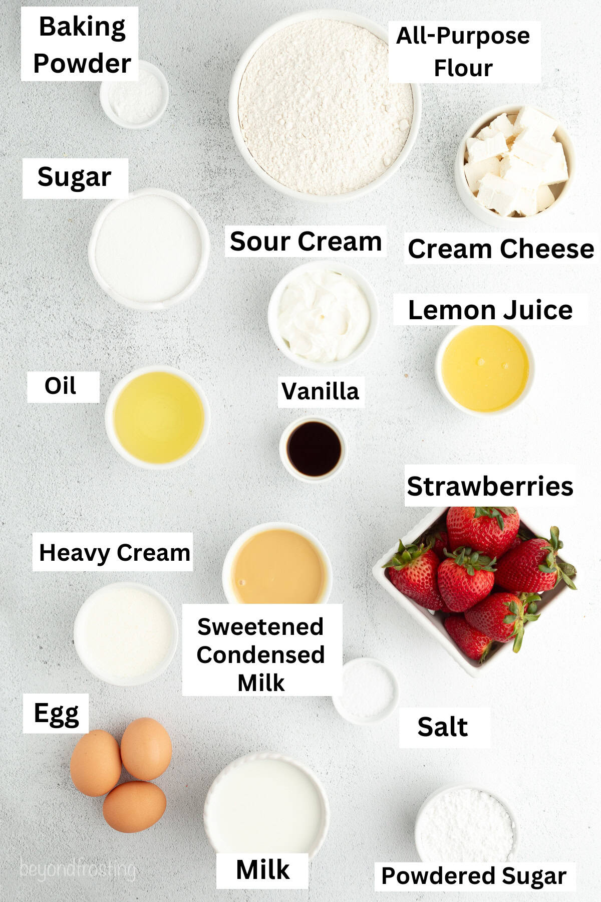 Strawberry cheesecake poke cake ingredients with text labels overlaying each ingredient.