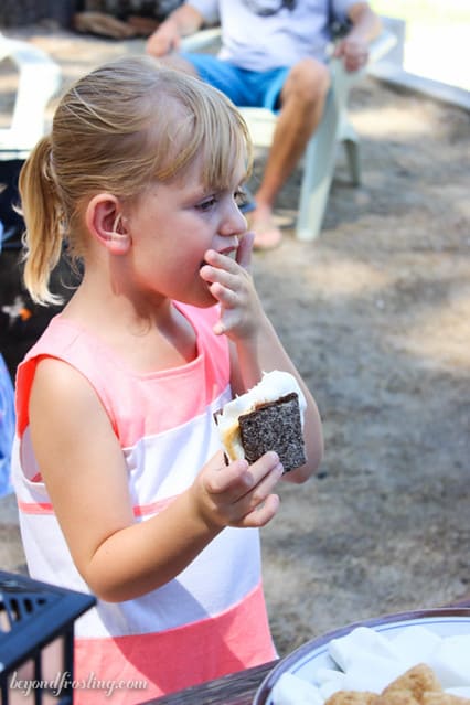A little girl licking her fingers while eating a S'more