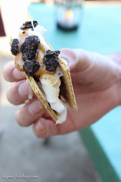 Close-up of a hand holding a s'more with chocolate crumbles on the marshmallow