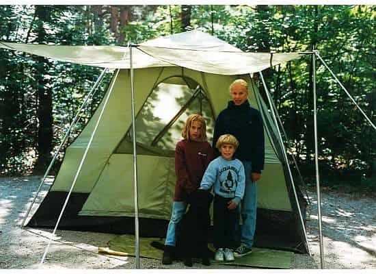 Three kids standing in front of a green tent
