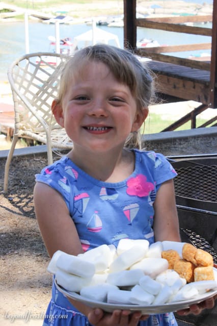 A little girl holding a plate of marshmallows and smiling