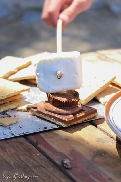 A marsmallow being added to a graham cracker with chocolate