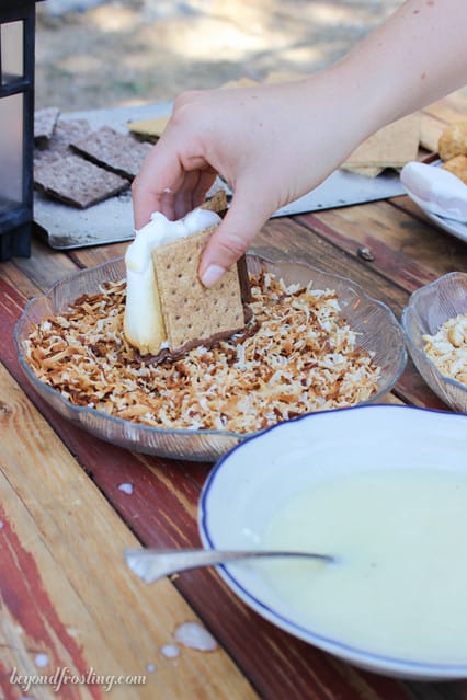 A s'more being dipped into toasted coconut