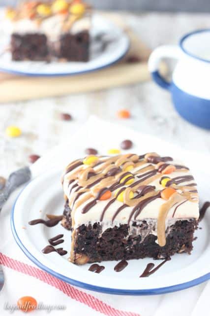 A Slice of Peanut Butter Poke Cake Topped with Peanut Butter Candies and Chocolate Peanut Butter Drizzle