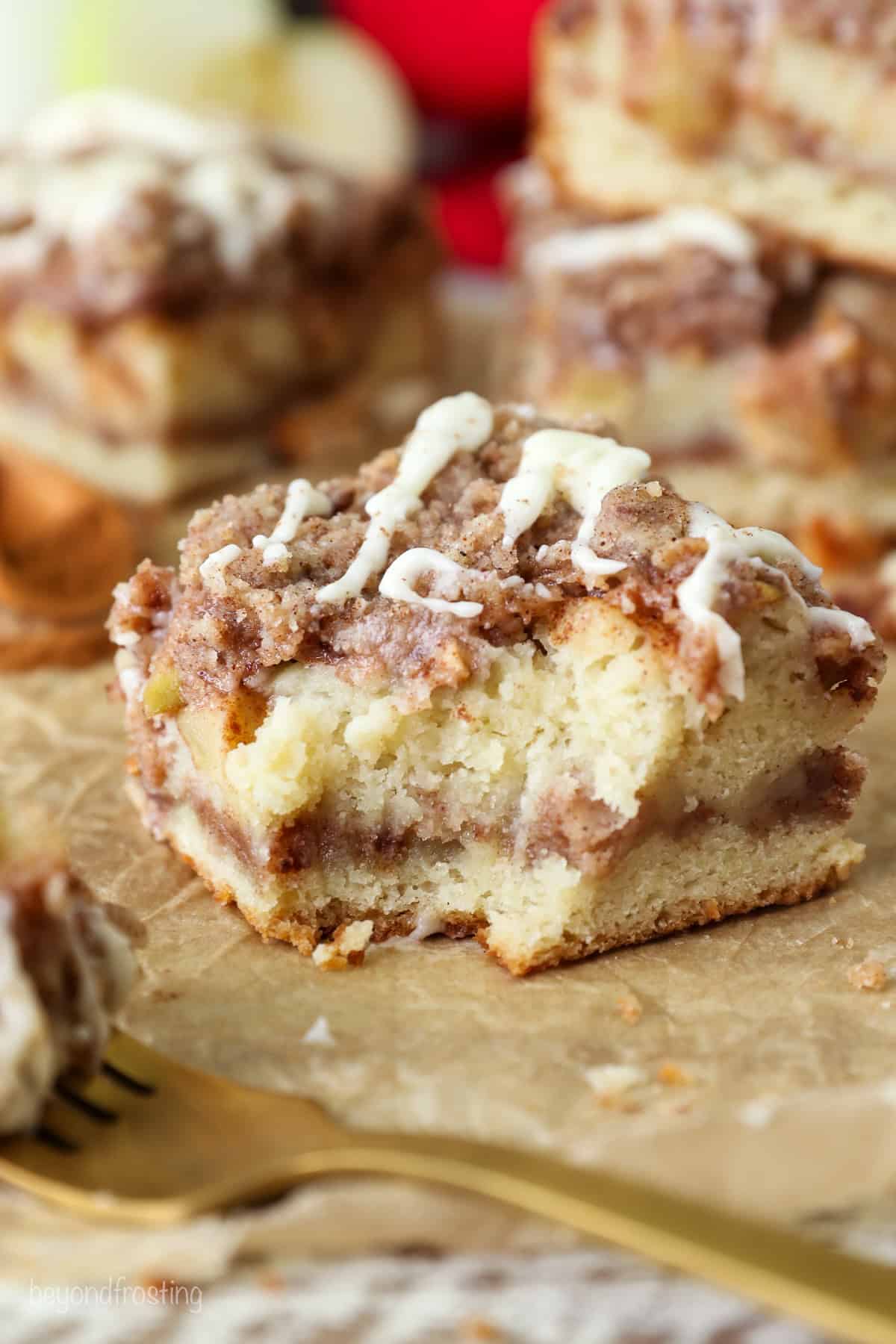 Close up of a slice of apple coffee cake with a bite missing, with more slices in the background.