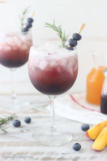 This Blueberry Peach Spritzer is an easy way to impress your friends with a homemade cocktail. A simple blueberry syrup is combined with peach juice concentrate and mixed with prosecco or seltzer. It can be garnished with additional blueberries or rosemary. 