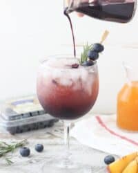 This Blueberry Peach Spritzer is an easy way to impress your friends with a homemade cocktail. A simple blueberry syrup is combined with peach juice concentrate and mixed with prosecco or seltzer. It can be garnished with additional blueberries or rosemary.