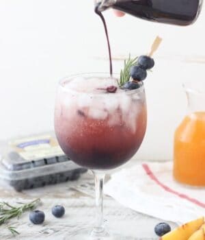This Blueberry Peach Spritzer is an easy way to impress your friends with a homemade cocktail. A simple blueberry syrup is combined with peach juice concentrate and mixed with prosecco or seltzer. It can be garnished with additional blueberries or rosemary.