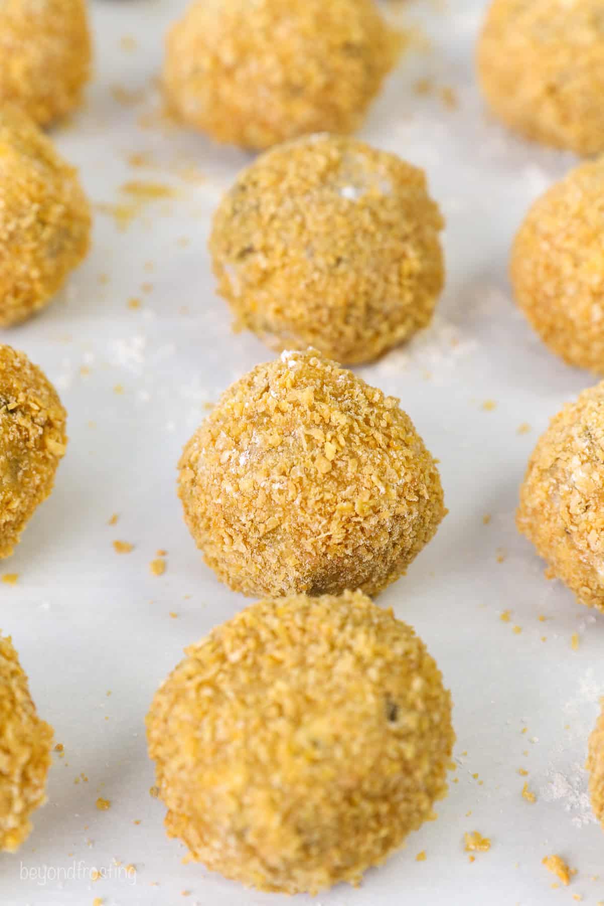 Rows of cookie dough balls coated with cornflake crumbs.
