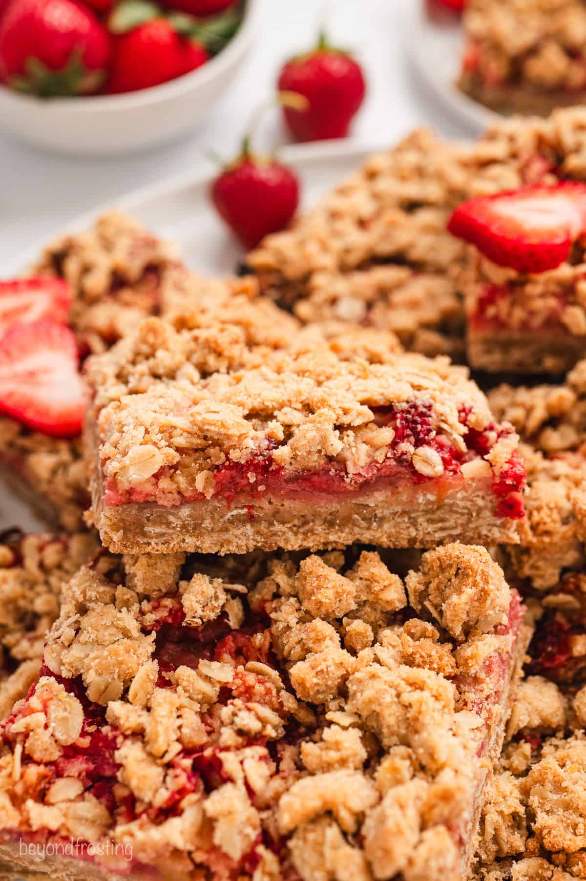 Assorted strawberry rhubarb bars stacked on a large platter.