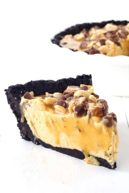 This Snicker Peanut Butter Oreo Pie will make you swoon. An Oreo crust is filled with smooth peanut butter filling and topped with Snickers, peanuts, caramel sauce and chocolate chips. 