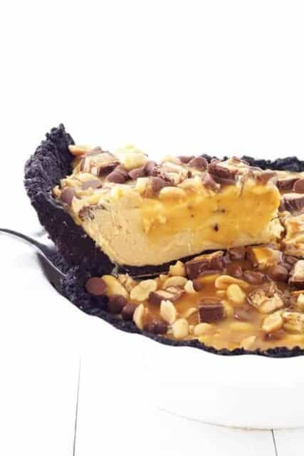 This Snicker Peanut Butter Oreo Pie will make you swoon. An Oreo crust is filled with smooth peanut butter filling and topped with Snickers, peanuts, caramel sauce and chocolate chips.