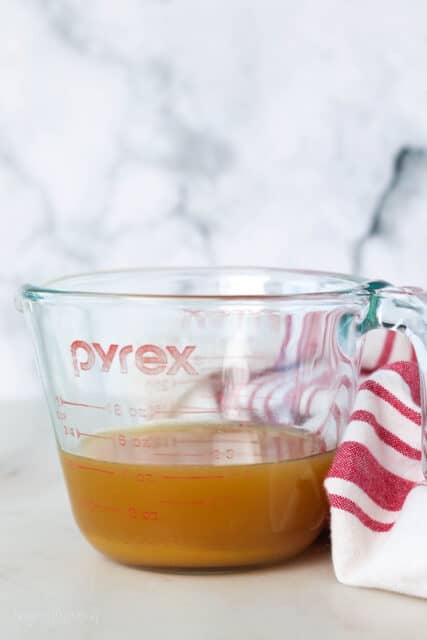 Reduced apple cider in a glass measuring cup.